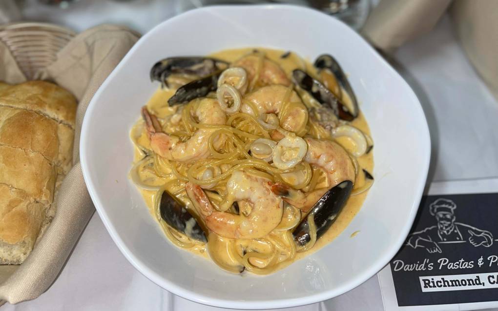 A plate of spaghetti topped with shrimp and mussels in a creamy sauce.