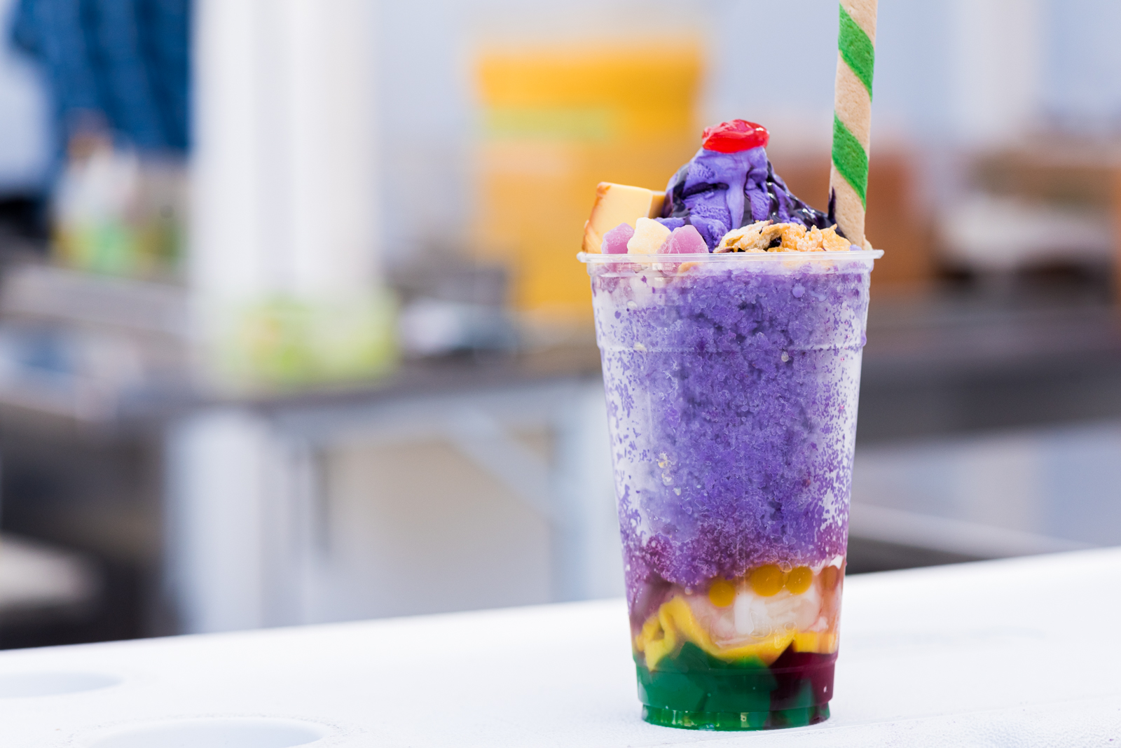 A cup of halo halo, with layers of bright purple ube ice cream, flan and sweet beans.