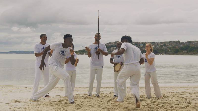 A group of capoeiristas are playing in the circle on a beach in Salvador, Brazil.