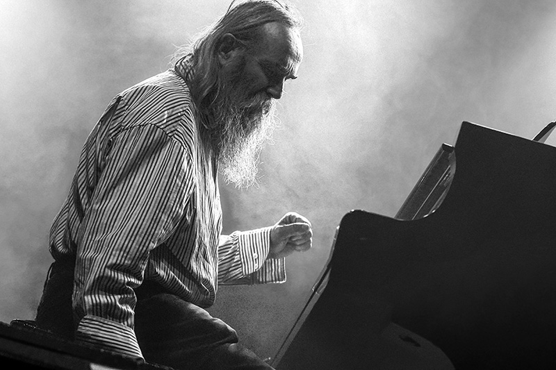 a black and white photo of a man sitting at a piano