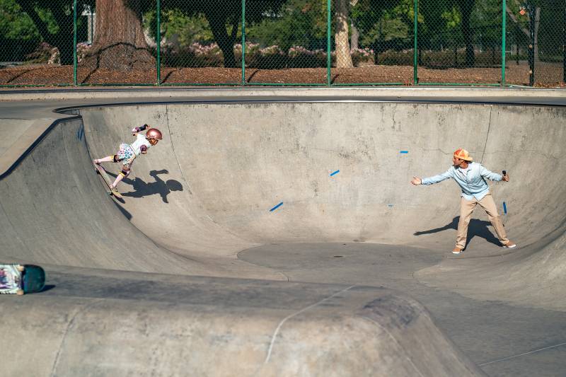 a young girl and a man do a trick in a skate park