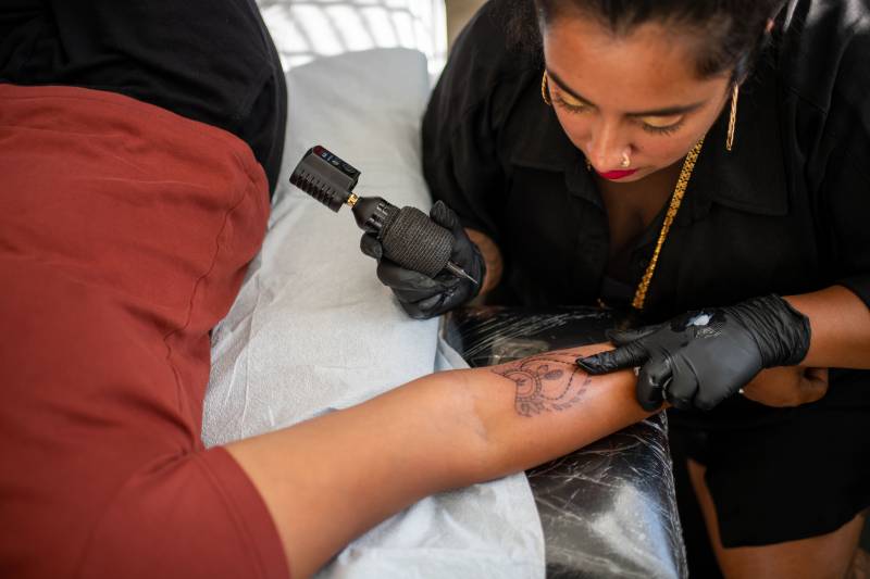 Sabreena Haque focuses as she does a tattoo on someone's forearm