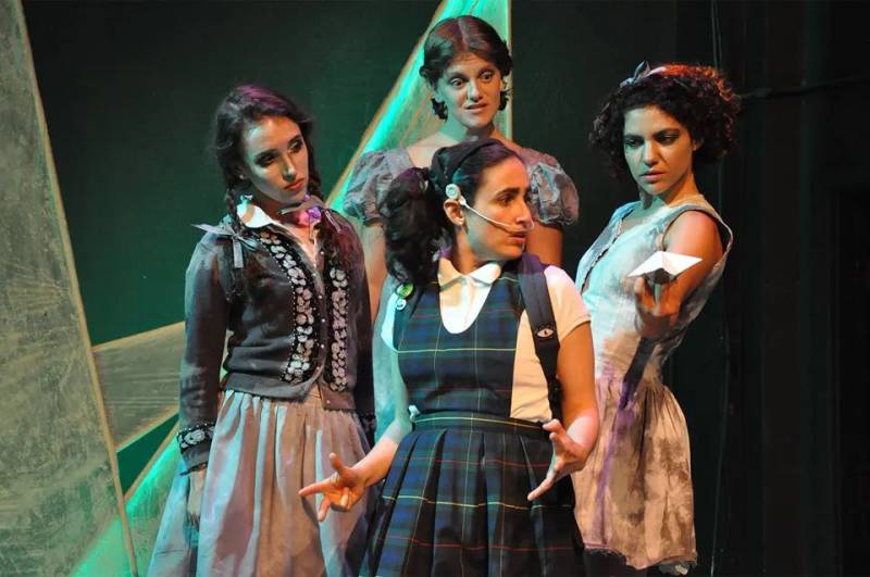 four women on stage in schoolgirl costumes in a play