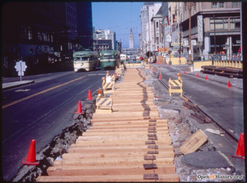 A series of wooden slats run the length of Market Street, surrounded by small orange cones as streetcars drive up the opposite side of the road.