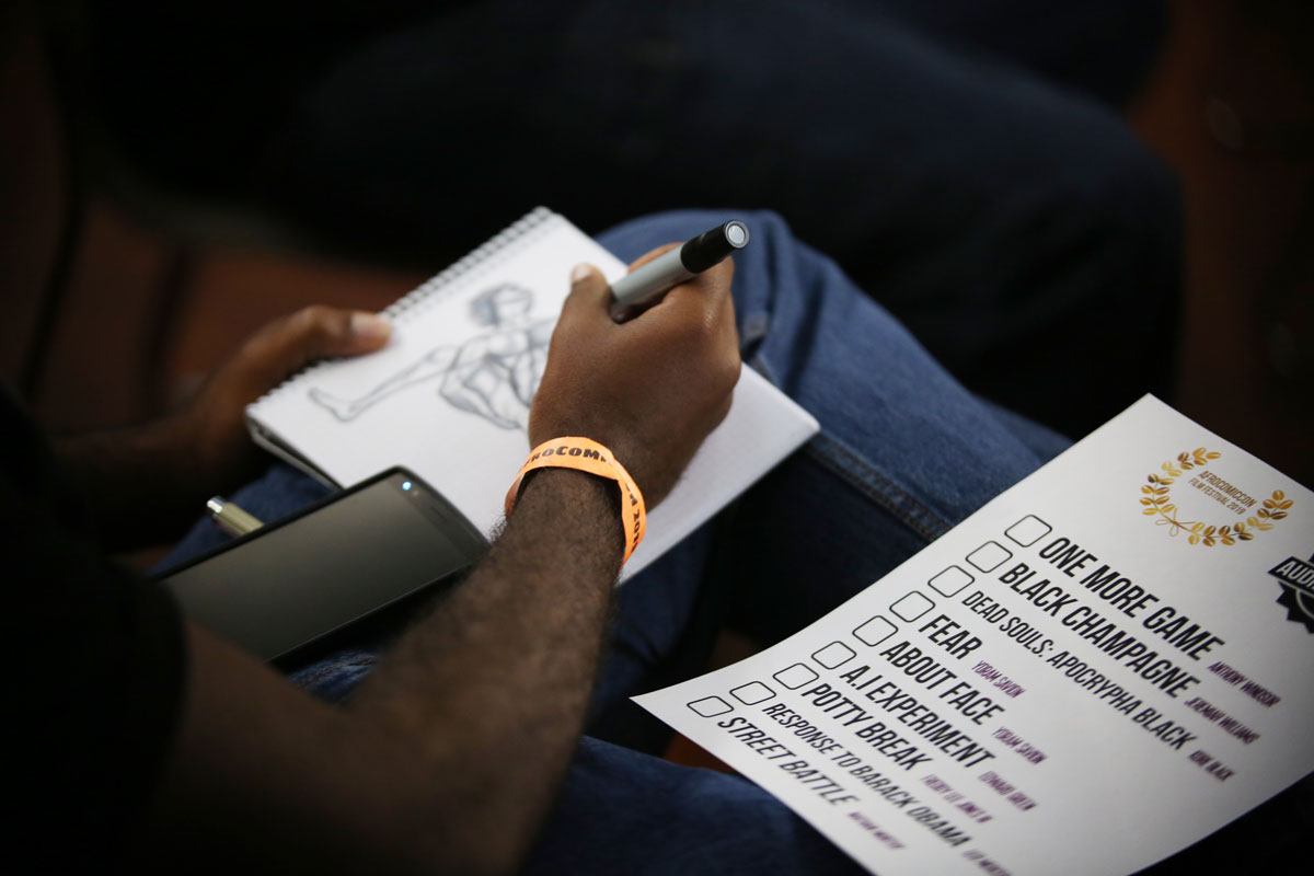 View of person drawing with a checklist of AfroComicCon by their side