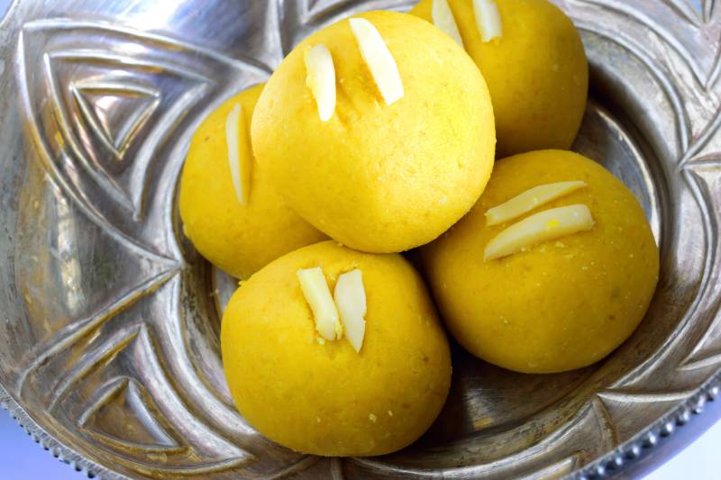 Small round yellow dessert balls, each topped with two thin strips of almond.