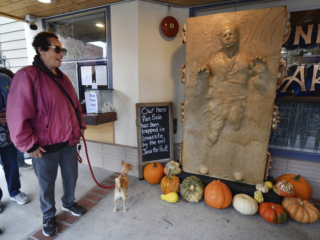 A woman waits in line as her dog glances up at a sculpture of 'Star Wars' character Han Solo.