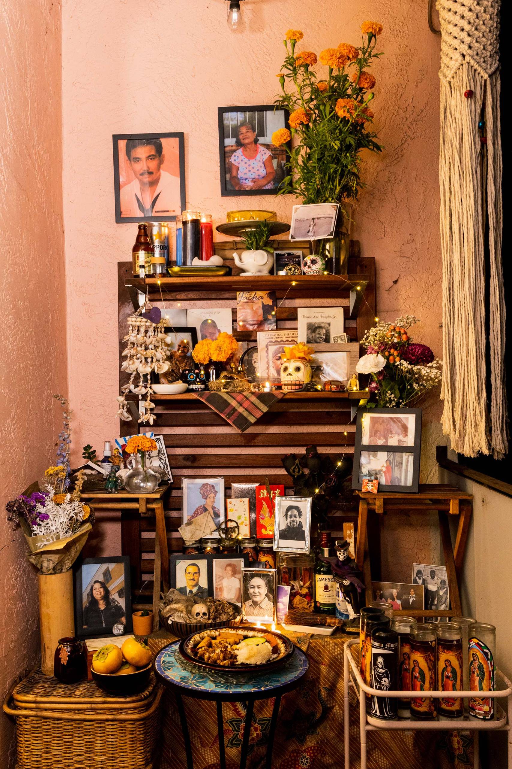 A home altar to honor ancestors, covered with framed photographs, decorative skulls, and food offerings.