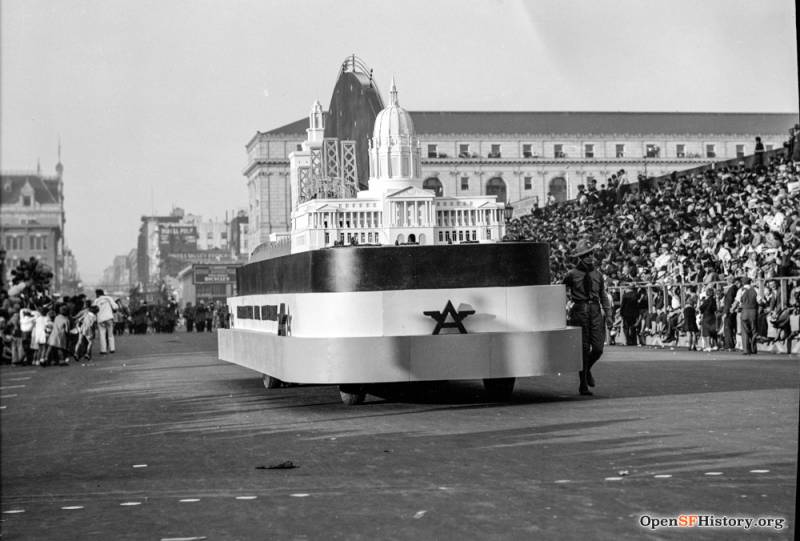 A float carrying a replica of San Francisco's city hall, plus the new Bay Bridge rolls past spectators.