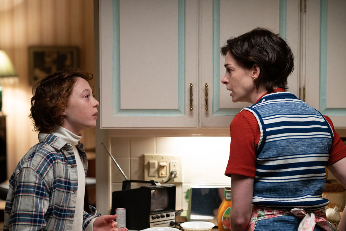 Red-headed white boy and white woman face each other tensely in kitchen
