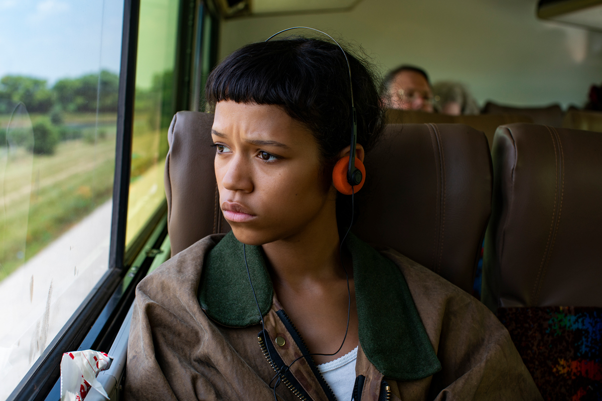Young Black woman with short bangs on bus with headphones on