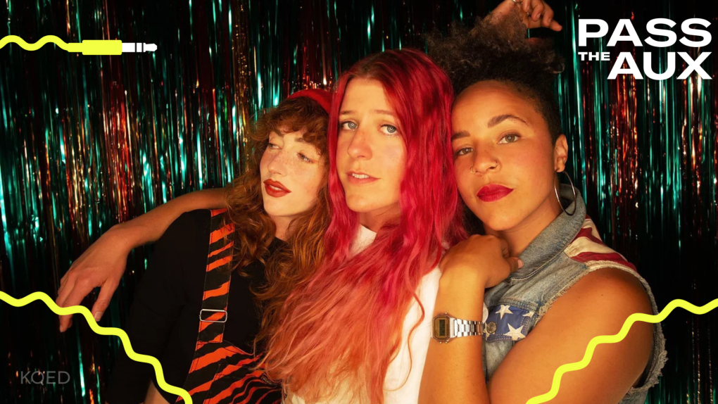 a trio of women pose in front of a colorful foil backdrop