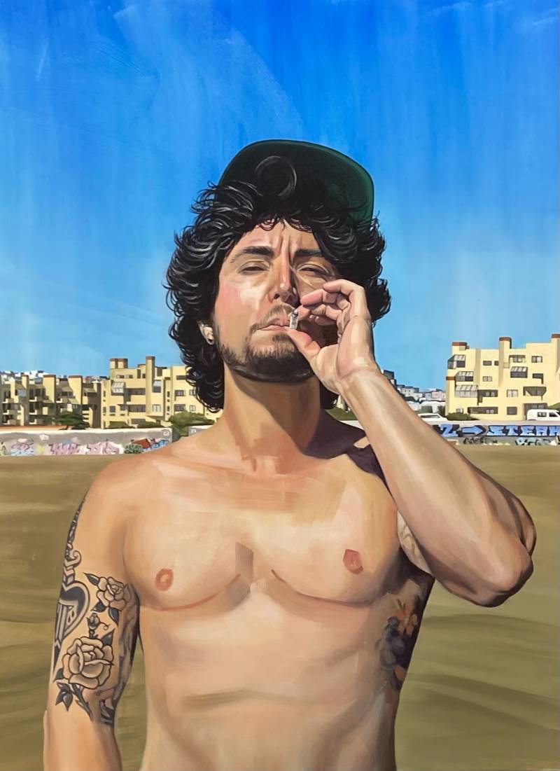 A painting of a shirtless, tattooed, smoking man wearing a baseball cap pushed back over shaggy hair. He is standing on the beach, under a blue sky and in front of a graffiti covered wall and buildings off in the distance.