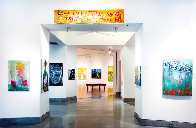 Paintings line an entryway into a gallery space