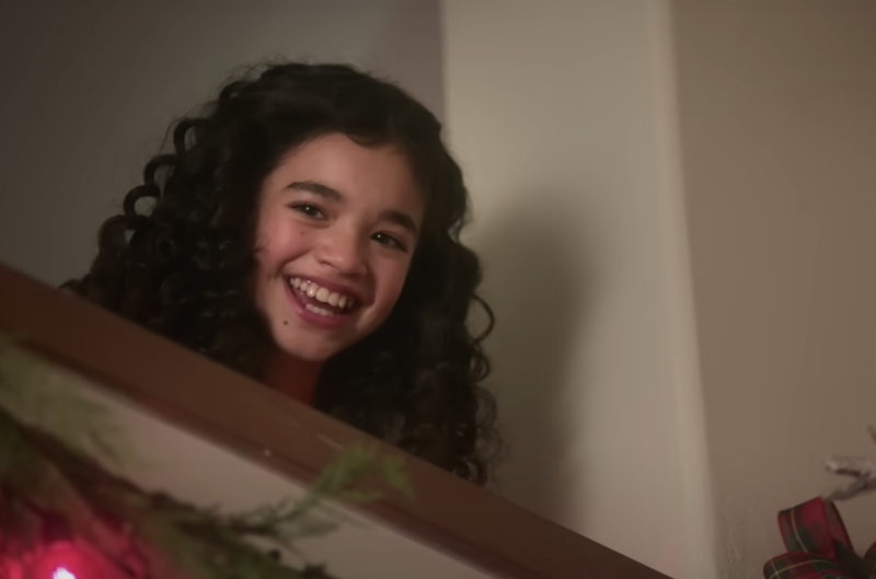 An adorable child with dark curly hair smiles broadly.