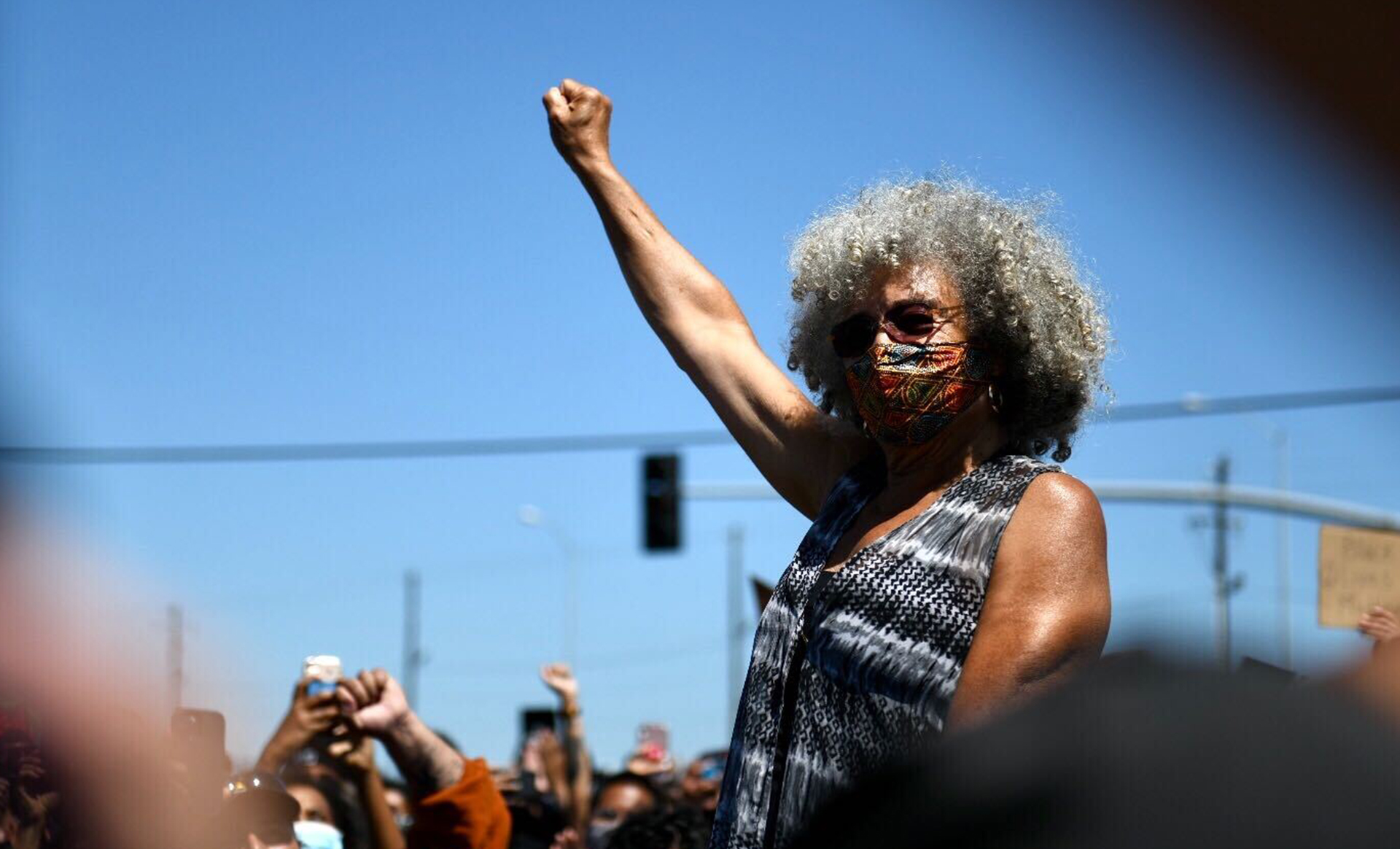 Black woman in face mask raises right arm in solidarity