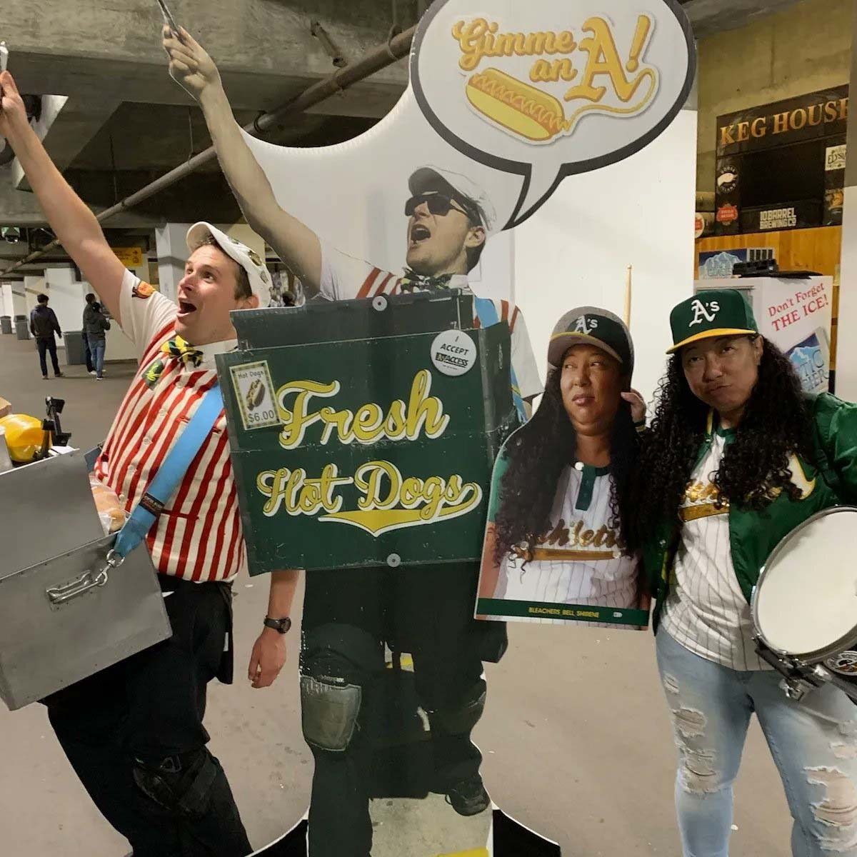 Hot dog vendor and a fan pose dramatically next to cardboard cutouts of themselves.
