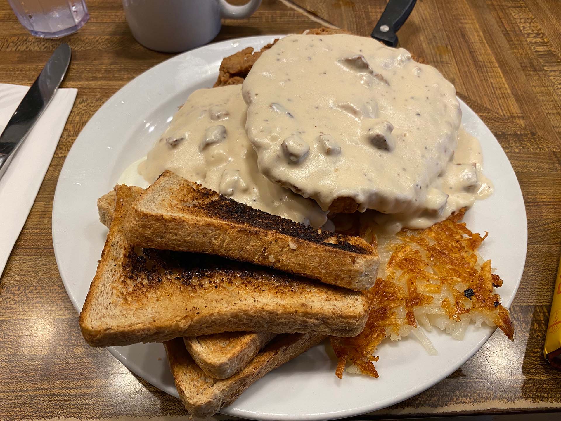A plate of chicken fried steak, toast and hash browns.