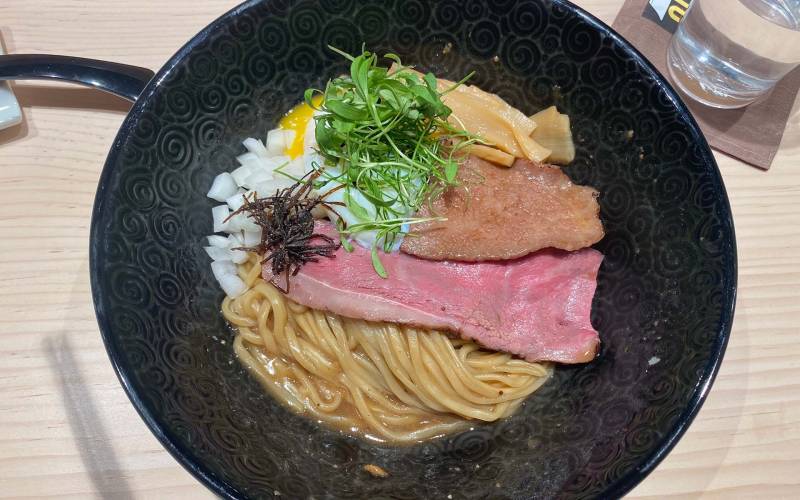 A bowl of soup-less ramen, with thick noodles and a topping of two different cuts of wagyu beef.
