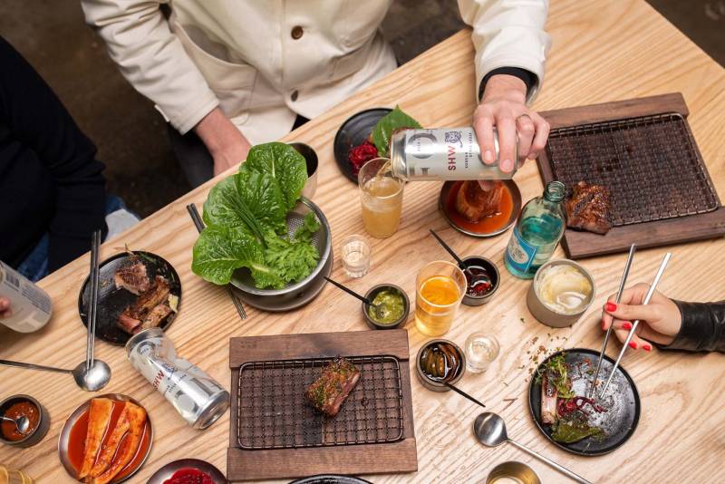 a table of Korean food with a beer being poured into a glass