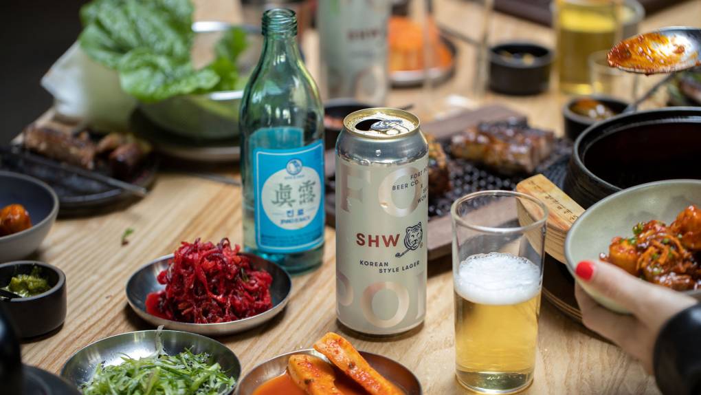 a table of Korean food that features San Ho Wan's new Korean lager beer at the center