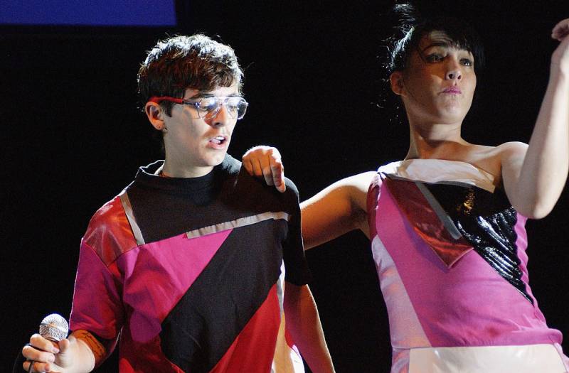 two people in black white and pink outfits perform on a stage