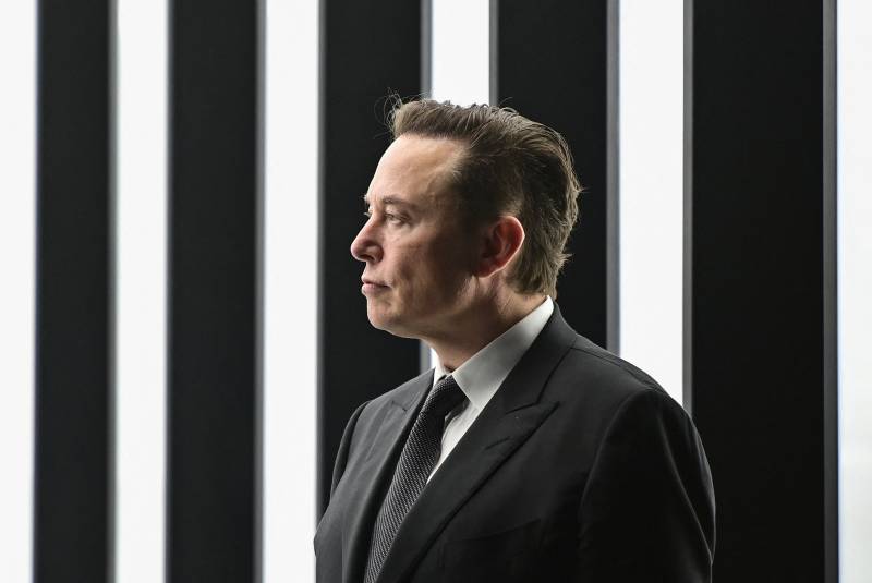 White man in black suit against black and white vertically striped background