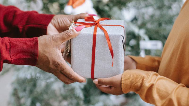 An older person's hands place a Christmas gift into a child's hands.