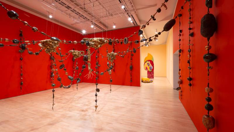 Orange walls with hanging cast fruit sculptures