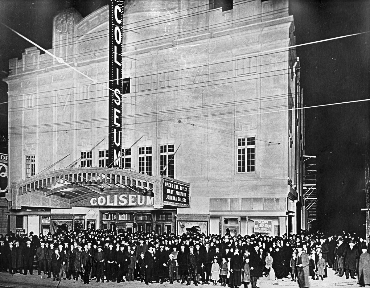 Black and white image of a large crowd in front of a movie theater
