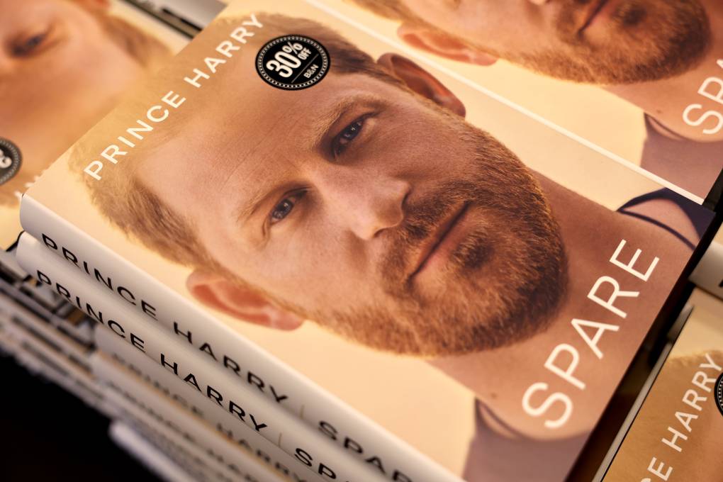 A stack of books featuring Prince Harry's face in close up, sit in a neat pile.