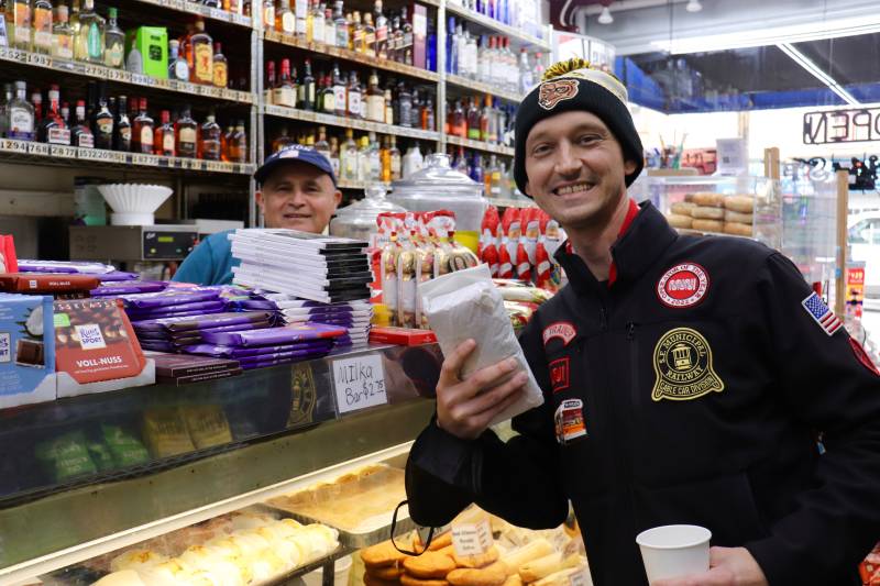 A Muni worker holds up a sandwich inside a deli in the Castro District