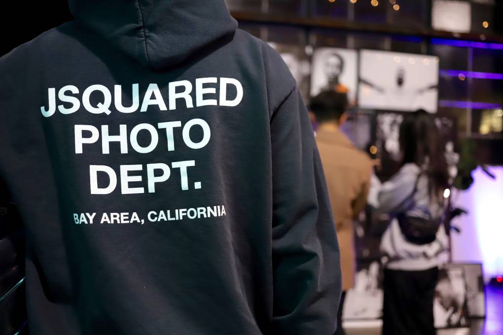 a young man wears a black hoodie that reads "Jsquared Photo Deptartment"