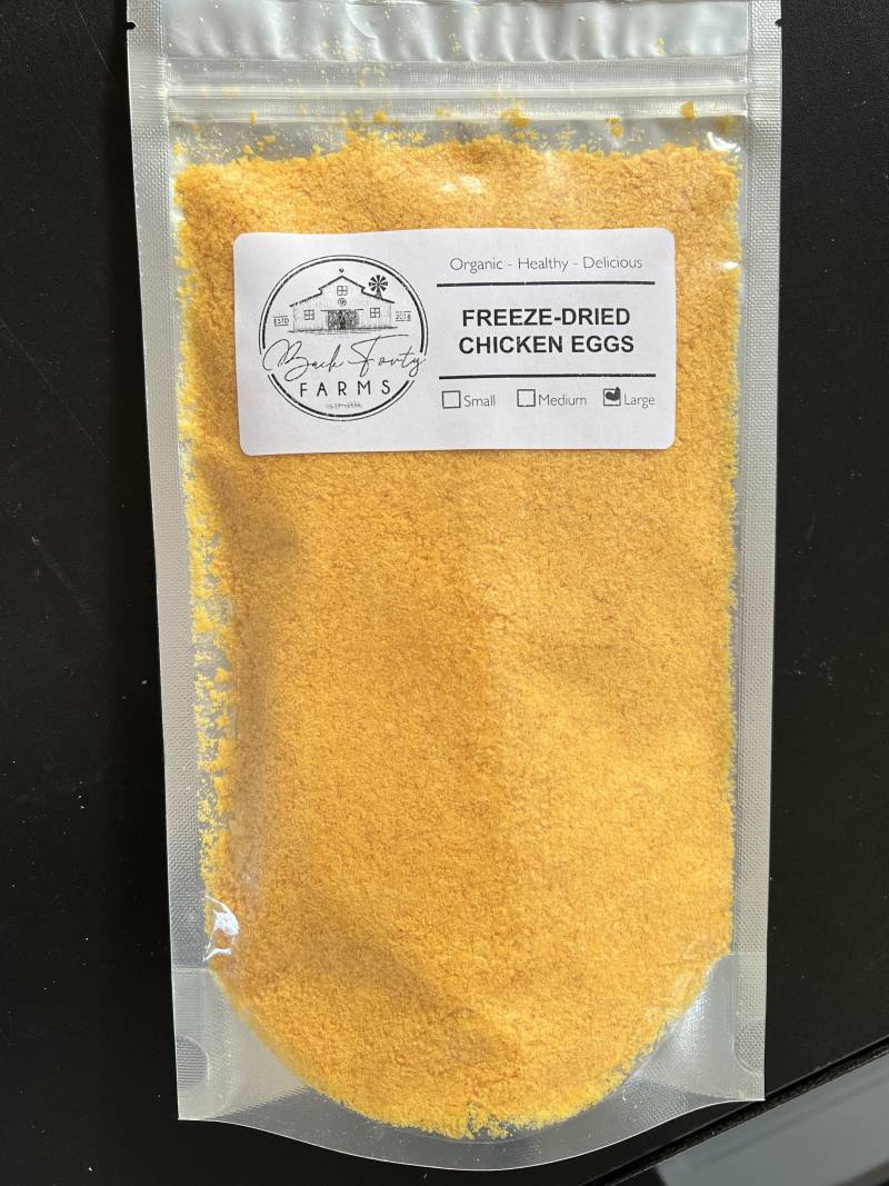 A vacuum packed bag of yellow food grains with a label reading FREEZE DRIED CHICKEN EGGS.