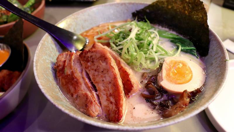 a bowl of ramen, with pork belly, seaweed, bean sprouts and more