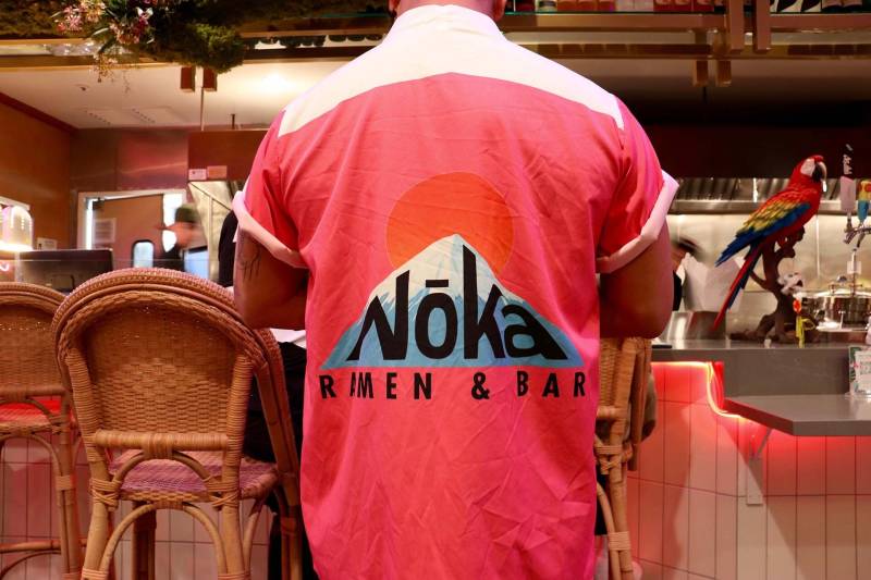an employee at Noka Ramen wears his uniform while serving a customer