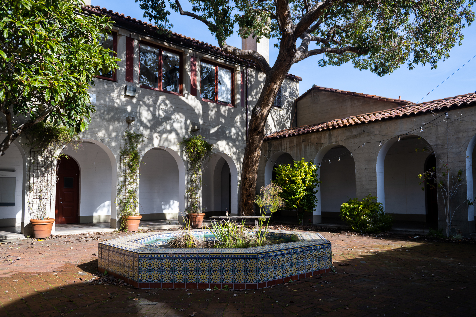 Empty Italianate courtyard with trees, fountain and shadows