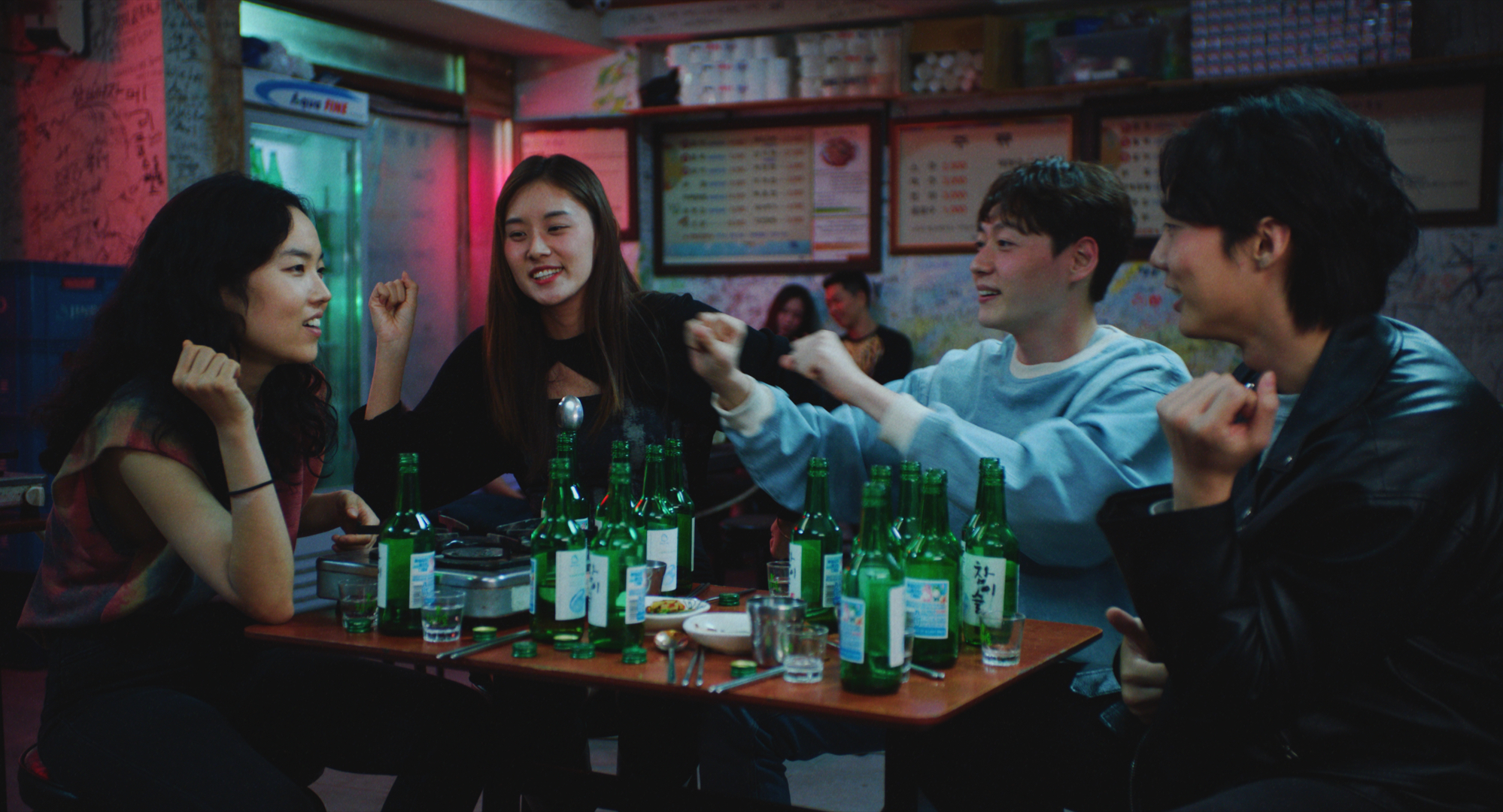 Four Asian young people sit cheerily around table of empty beer glasses