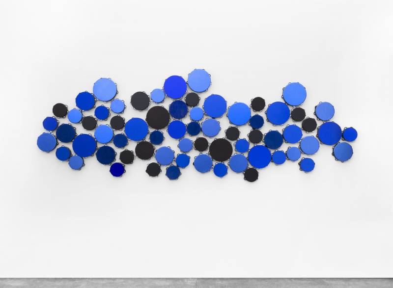 a textile work shows different sizes and shades of blue circles on a white background