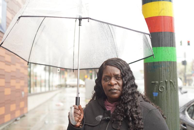 Arieann Harrison, CEO of The Marie Harrison Community Foundation, holds an umbrella in the rain while standing on Third Street in Bayview-Hunters Point.