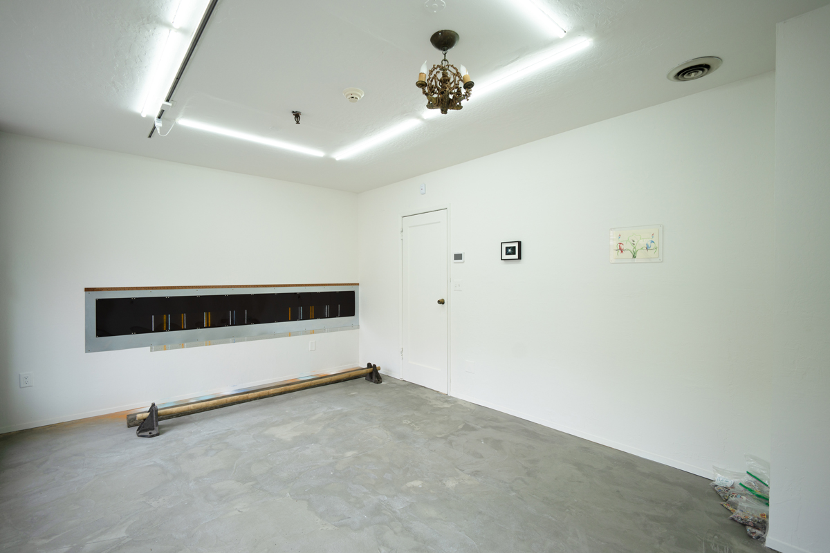 Interior view of white walled gallery with floor and wall work under fluorescent lights