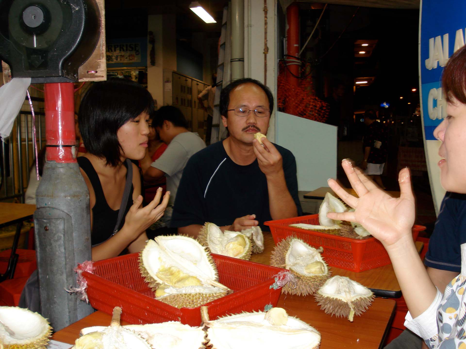 Durian eaters hold up sticky fingers at a durian stall in Singapore.