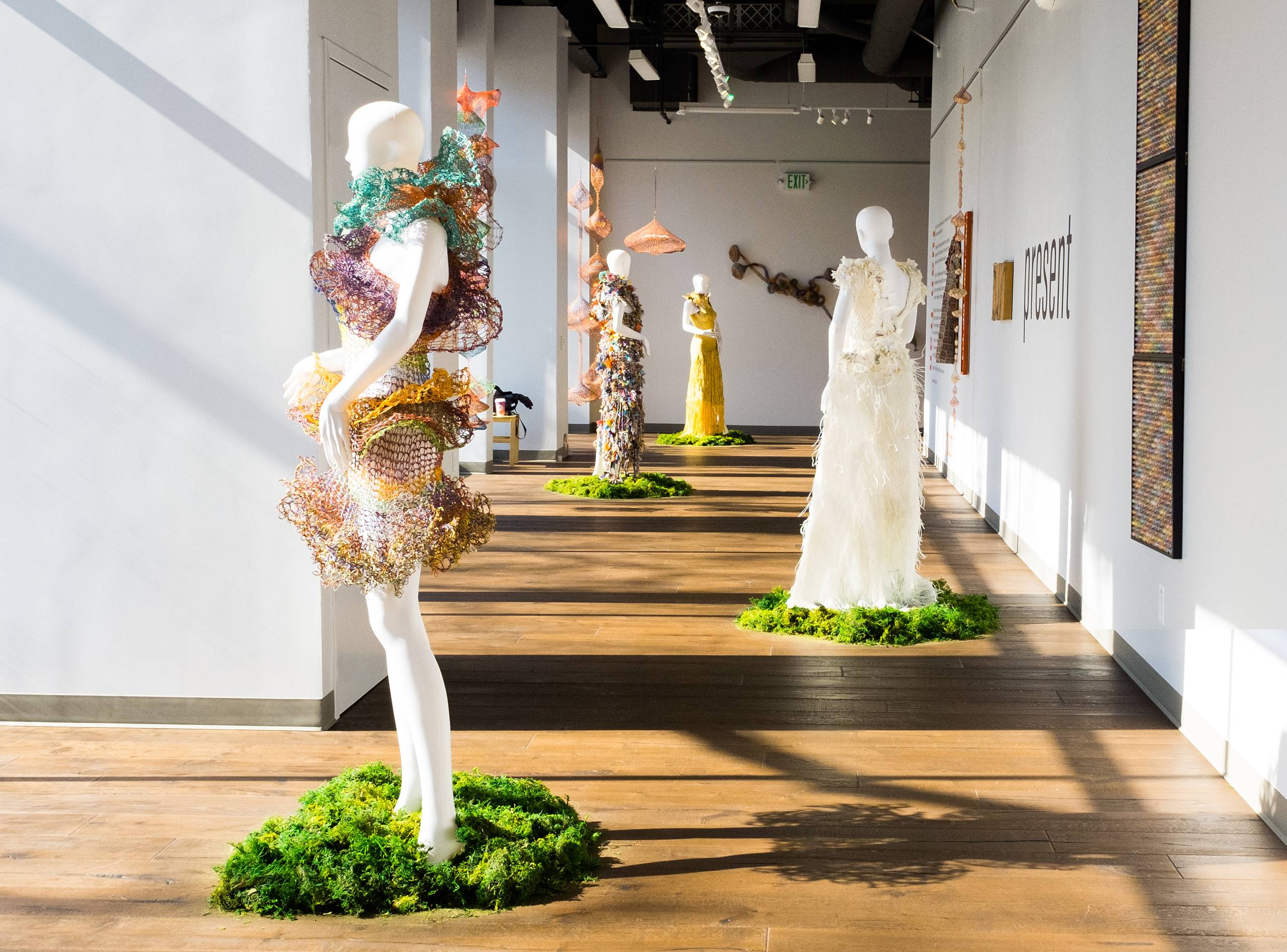 Sunny view of long gallery space with four mannequins in dresses