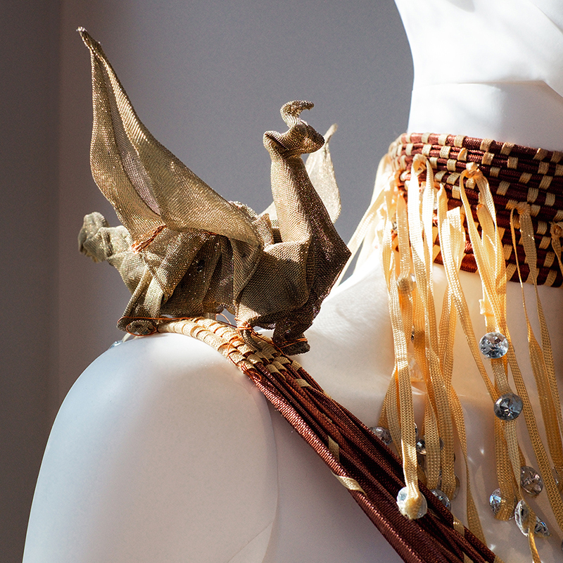 Mesh origami-like sculpture of a dragon on shoulder of mannequin
