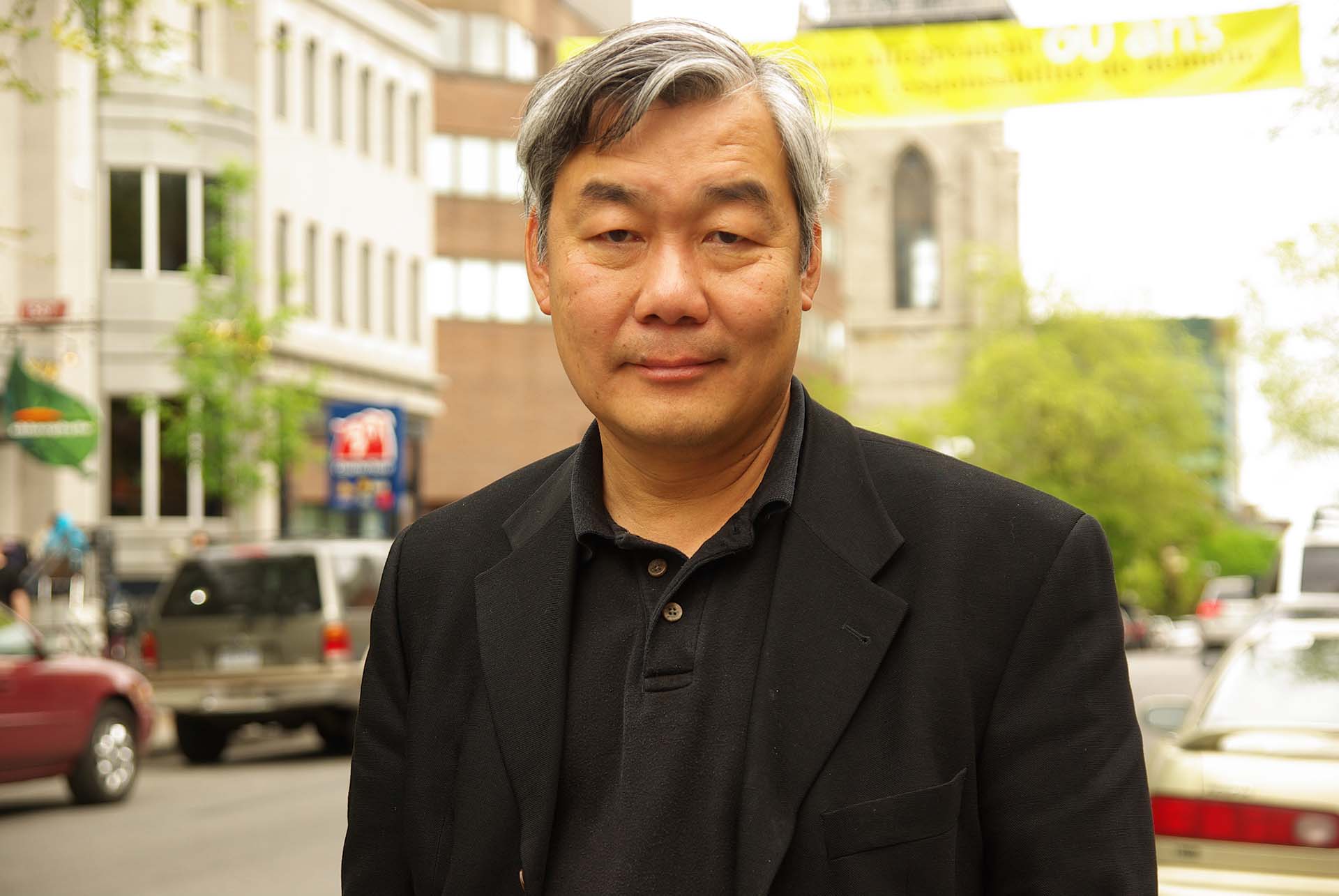 The author and documentary filmmaker Cheuk Kwan poses for a portrait in a black sports coat.