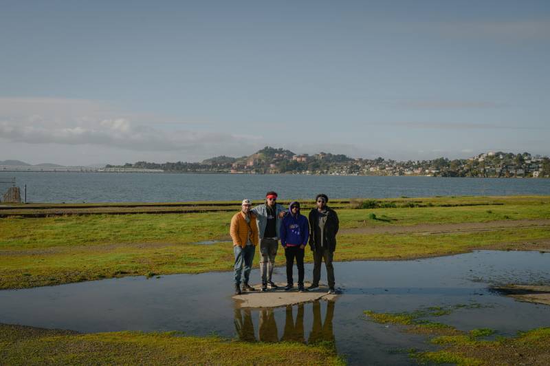 A group of rappers stand in front of the San Pablo Bay