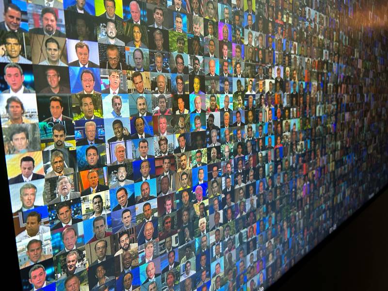 a large screen shows hundreds of tiny colorful images of news reporters 