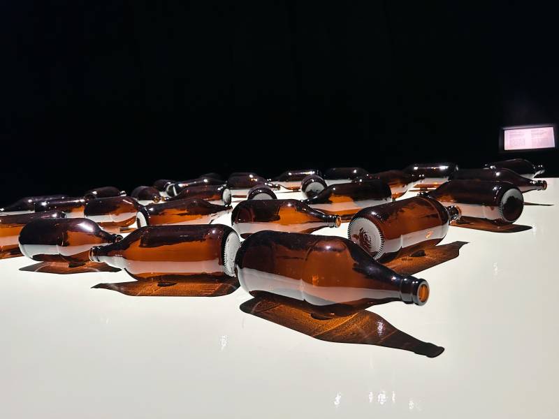 empty large brown bottles are positioned on a table in an art exhibit