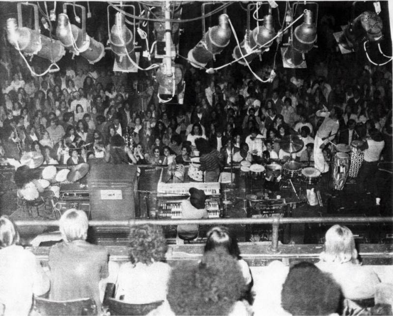 An overhead shot of Dakila performing in front of a large club crowd. 