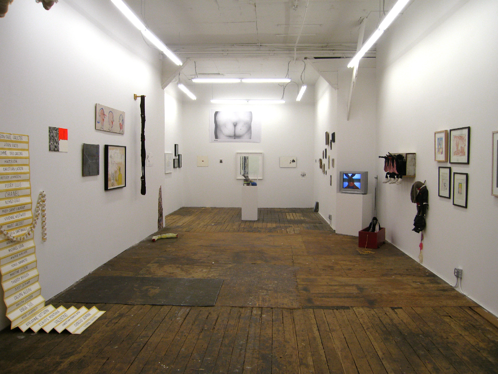Wood floored gallery with eclectic mix of wall work, sculpture and video